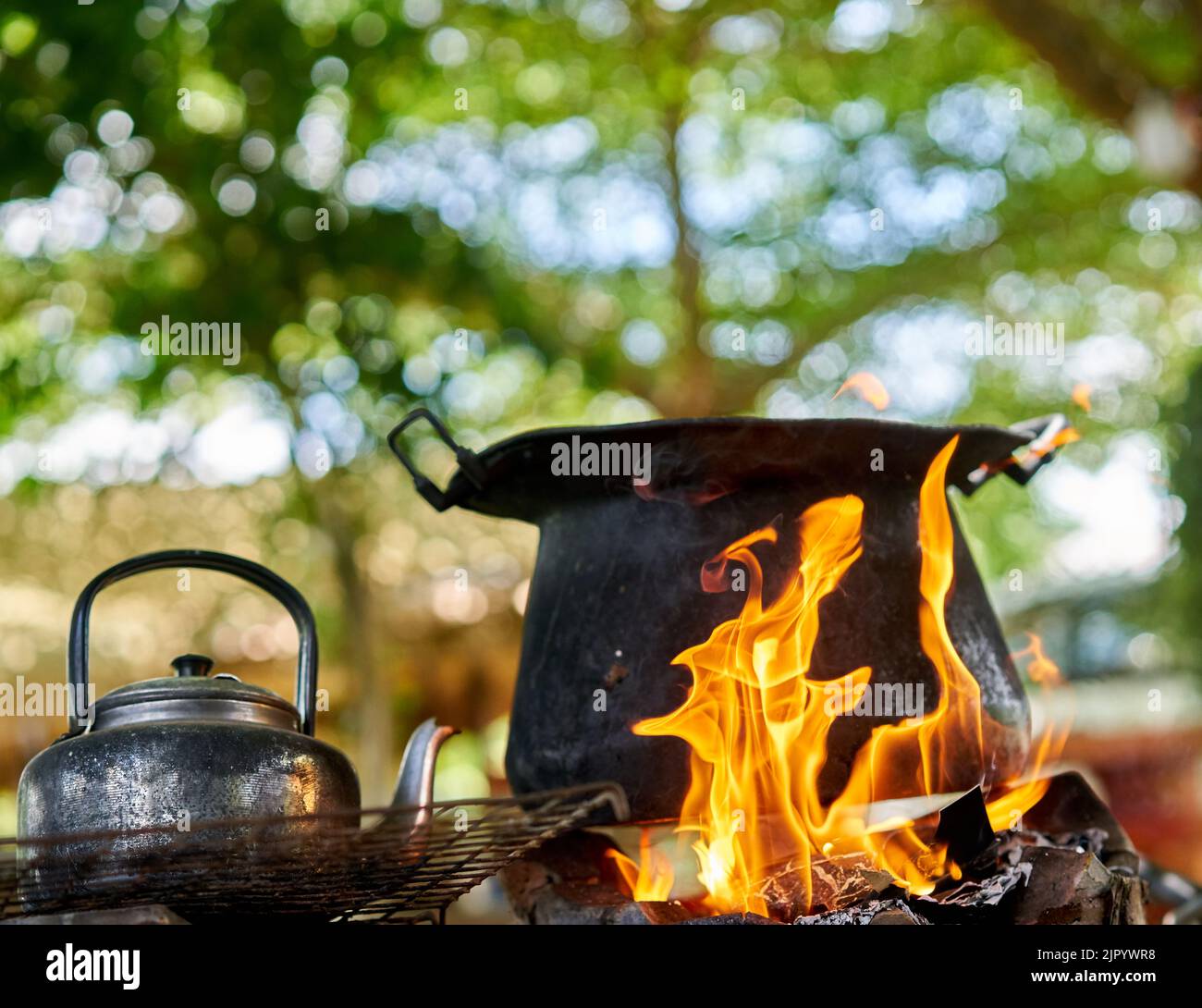 Una grande pentola nera e un vecchio bollitore su un fuoco all'aperto. Foto Stock