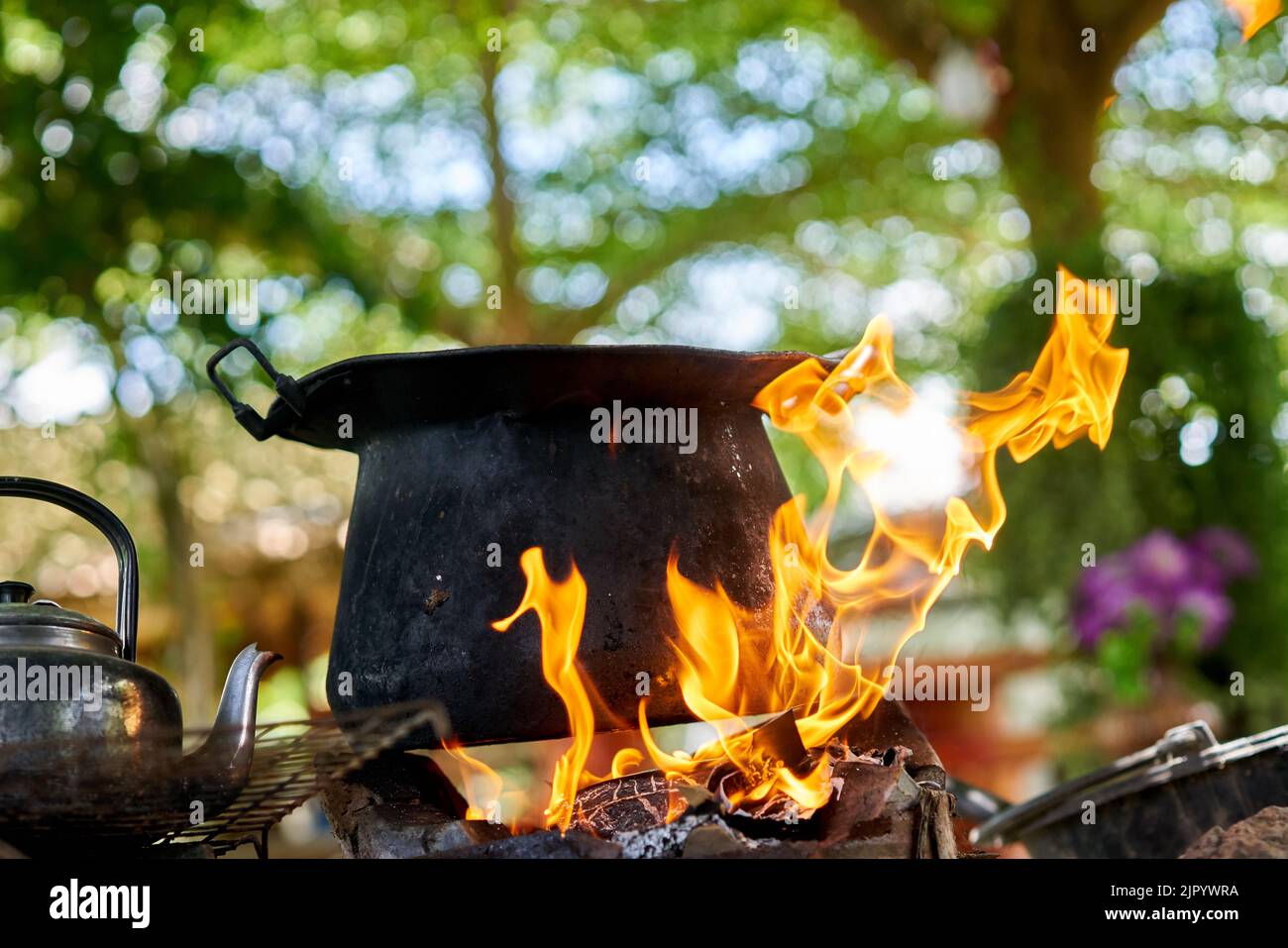 Una grande pentola nera e un vecchio bollitore su un fuoco all'aperto. Foto Stock