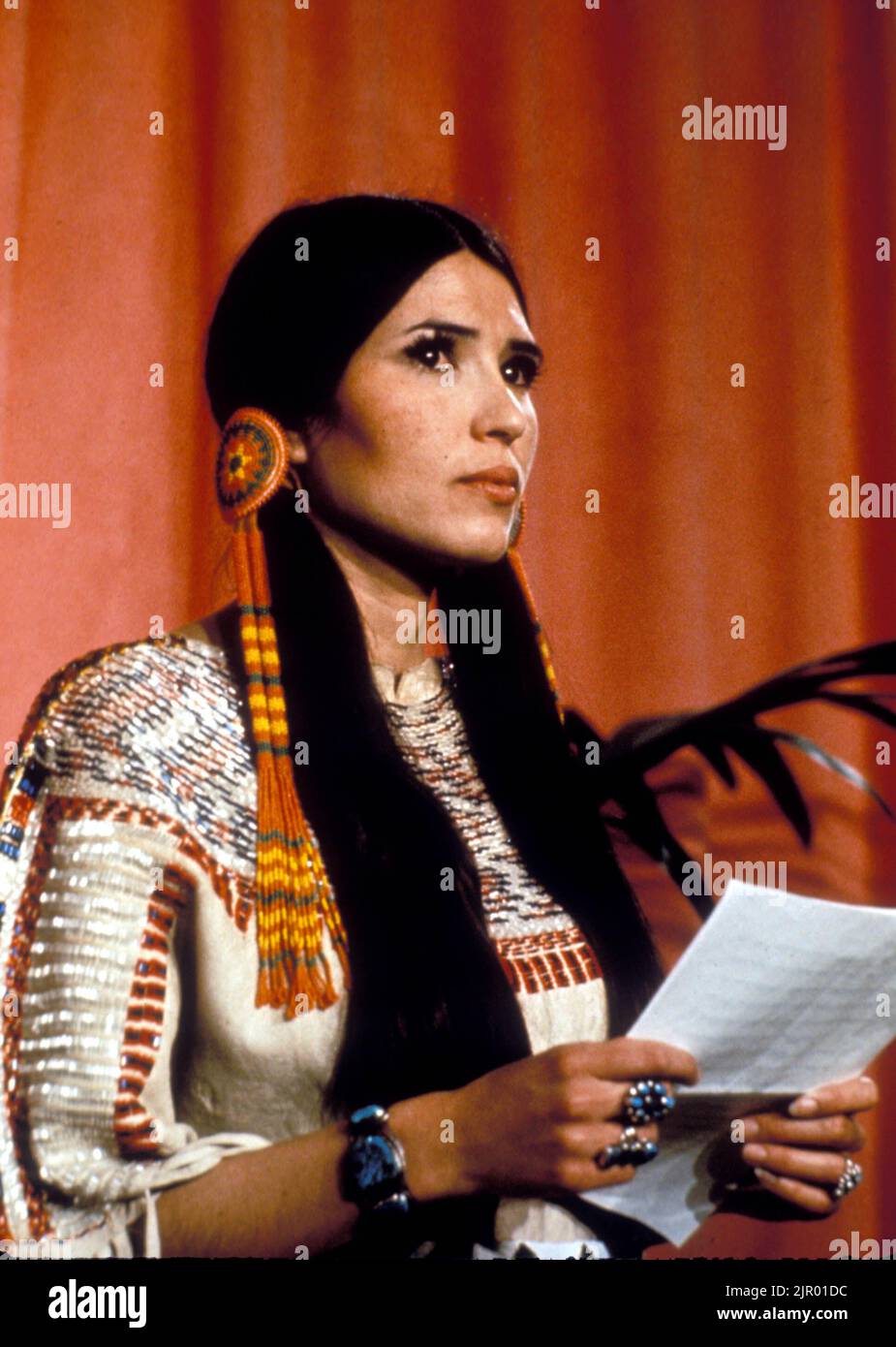 27 marzo 1973, Los Angeles, California, Stati Uniti: E l'Oscar va a... Ha poi tenuto un discorso di accettazione da parte di una giovane attrice/attivista SACHEEN LITTLEFEATHER, 26, Academy Awards al Dorothy Chandler Pavilion. Indossando un abito in pelle di fibbie e mocassini, sul palco, spiega solennemente che Brando “con grande rammarico” non poteva accettare il premio a causa del “trattamento riservato oggi agli Indiani americani dall’industria cinematografica”. Alcuni membri del pubblico si sono scontrati. Altri hanno fatto il booed. Senza essere afflitti, ha aggiunto Littlefeather, il rifiuto di Brando all’Oscar è stato anche indotto dall’occupazione di Wired Knee da parte degli attivisti dei nativi americani Foto Stock