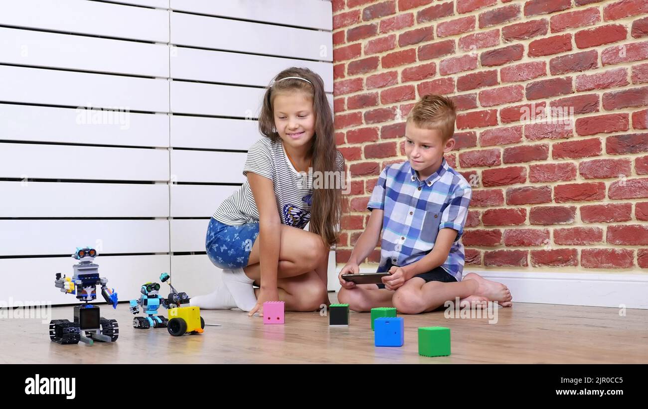 bambino di sette anni gioca a robot elettronici, auto, giocattoli moderni sul radiocomando. nuove tecnologie nel settore dei giochi per bambini. piccoli geni. Foto di alta qualità Foto Stock