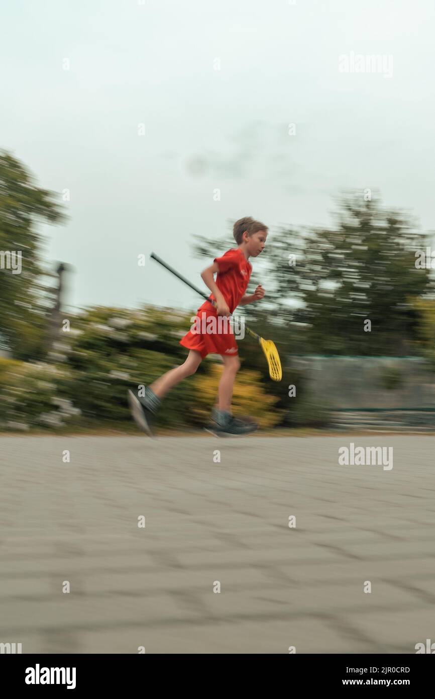 Un colpo verticale di un ragazzo caucasico catturato in movimento durante il gioco del floorball Foto Stock