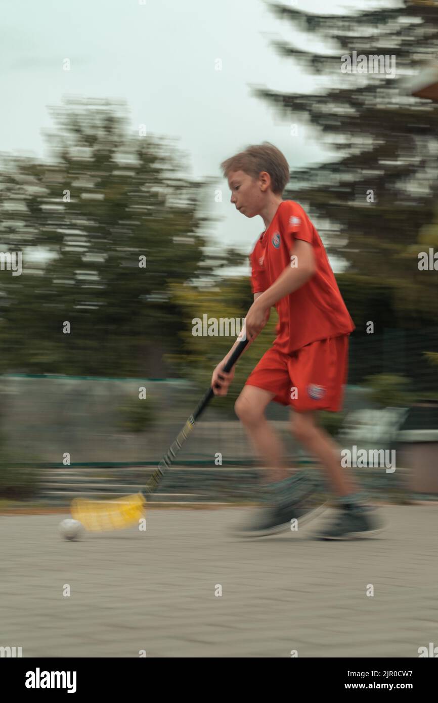Un colpo verticale di un ragazzo caucasico catturato in movimento durante il gioco del floorball Foto Stock