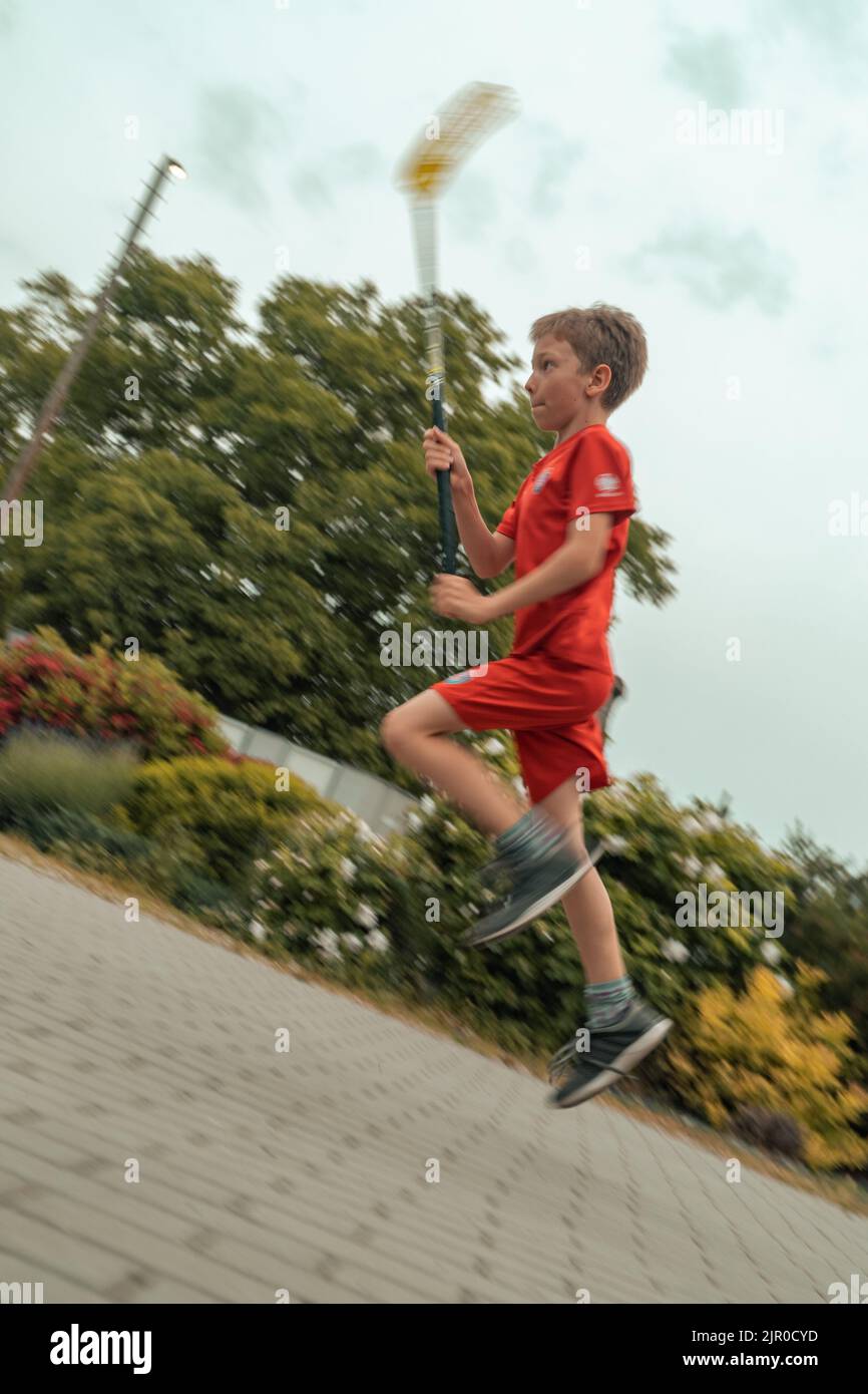 Un colpo verticale di un ragazzo caucasico catturato in movimento durante il gioco del floorball Foto Stock