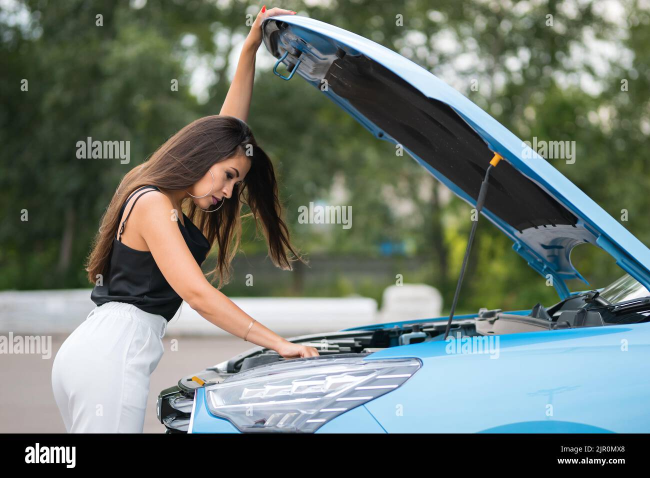 Autista donna d'affari cerca di riparare l'auto nel parcheggio Foto Stock