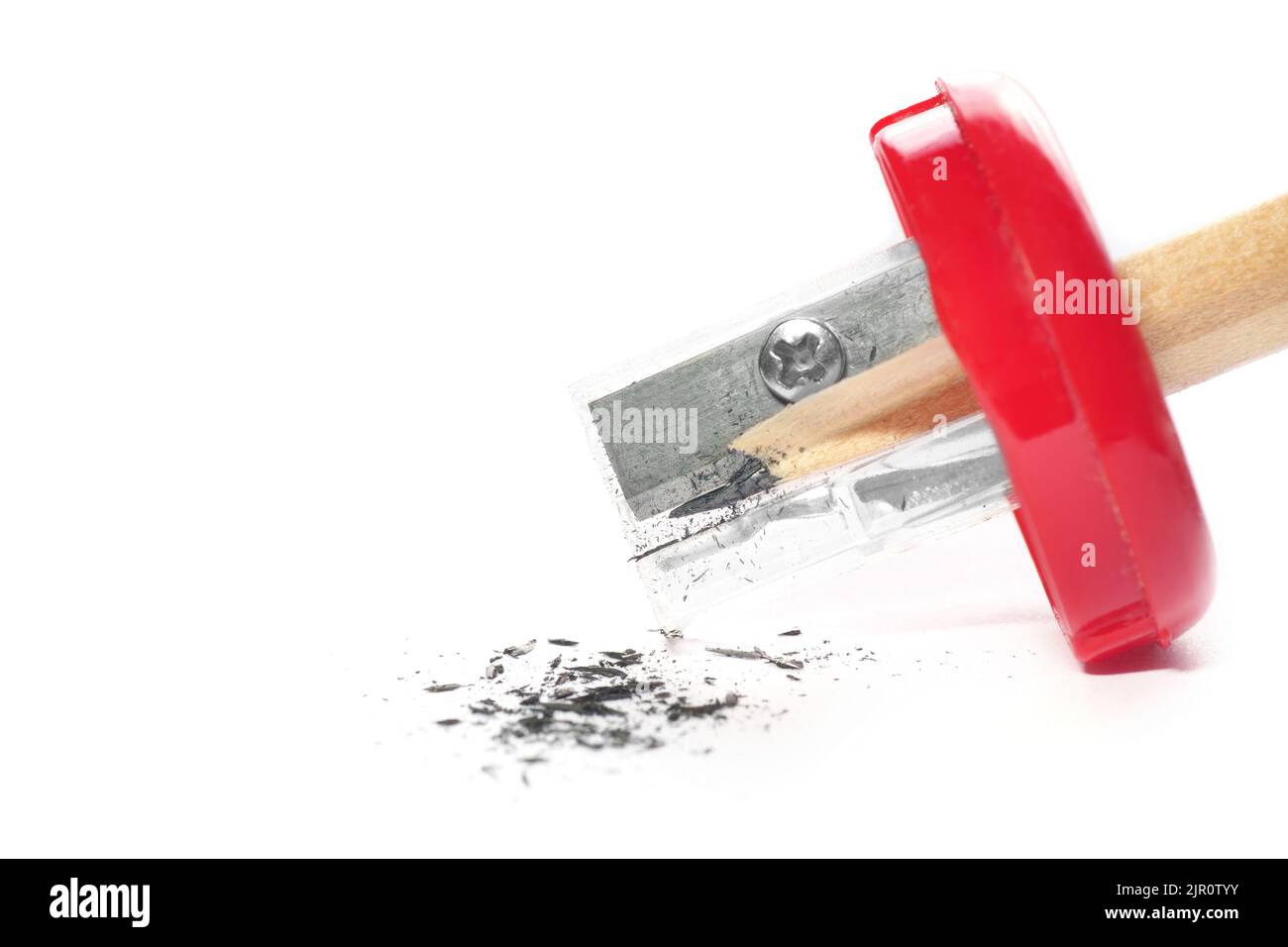 Primo piano della punta di una matita in un affilatore rosso isolato su sfondo bianco. Foto Stock