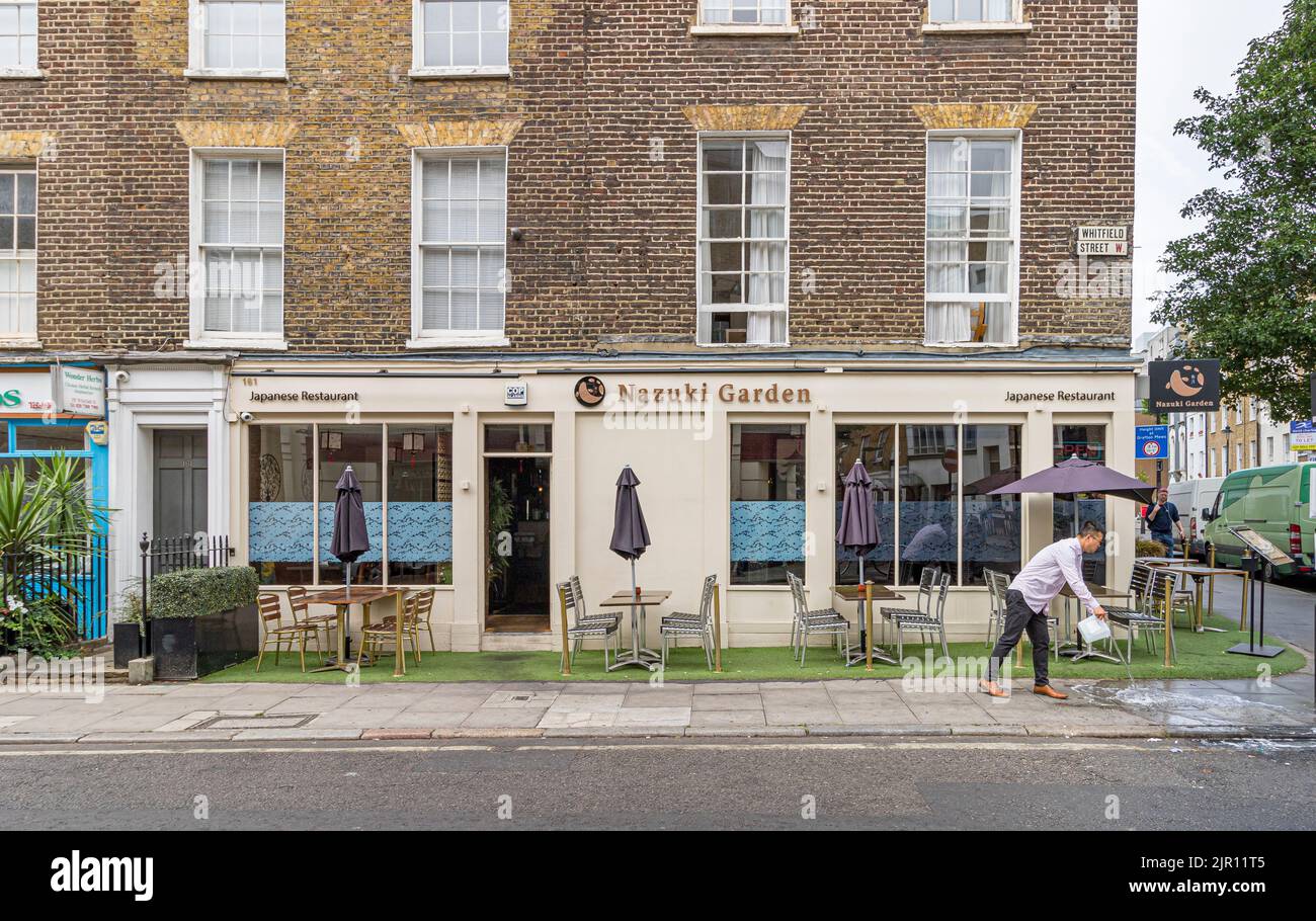 Un addetto al ristorante ha lavato il marciapiede fuori dal Giardino Nazuki e un ristorante giapponese in scala superiore a Fitzrovia, Londra W1 Foto Stock