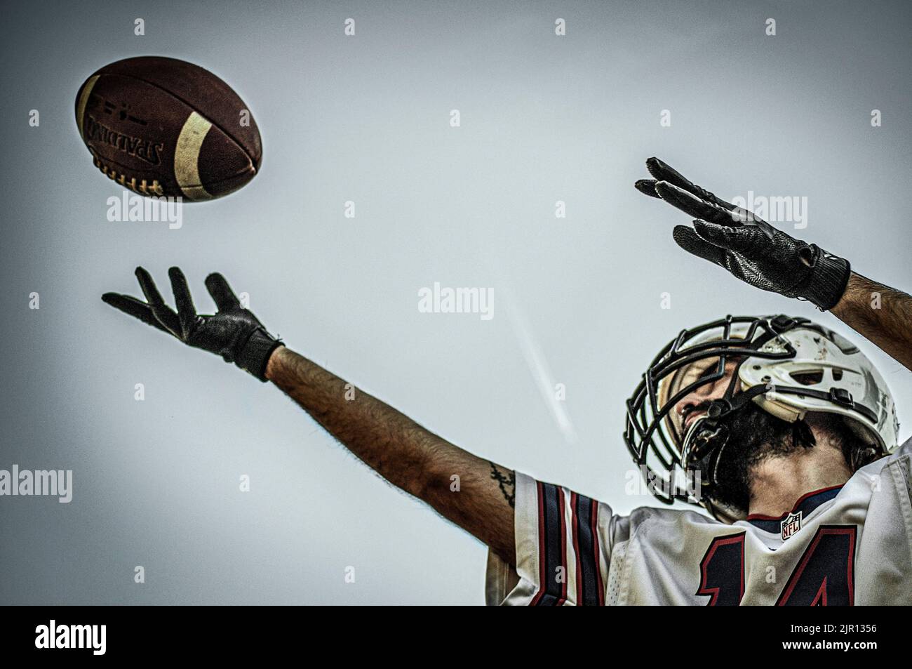 Giovane uomo che cerca di catturare una palla di calcio americana. Gioco di calcio americano. Giocatore che lancia la palla. Gioco di calcio realistico Foto Stock