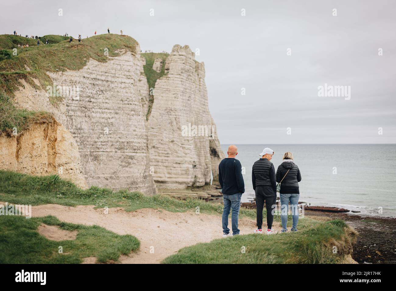 Una vista posteriore delle persone che si trovano sulla scogliera costiera in Francia con clima freddo Foto Stock