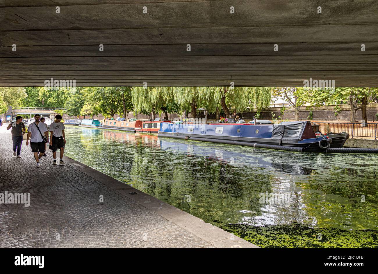 Un gruppo di persone che camminano lungo l'alzaia del Canal Grande Union a Paddington mentre passa sotto il Westway a Paddington, Londra, W2 Foto Stock