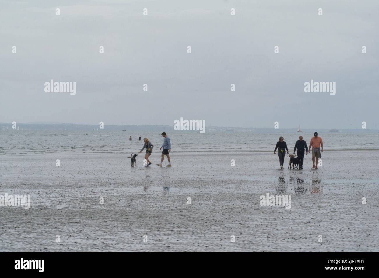 Tempo in Gran Bretagna, West Sussex, 21 agosto 2022: Nuvole, pioggia e alti di 21 gradi non scoraggia gli escursionisti con e senza cani, calciatori e pagaia da godersi la spiaggia di West Wittering. A differenza di altre spiagge del Sussex, l'acqua non è fuori limite, in quanto non ci sono stati scarichi di acque reflue locali. Nonostante la nuvola bassa e la pioggia intermittente, ci sono vedute dell'Isola di Wight e una regata nel Solent. Anna Watson/Alamy Live News Foto Stock