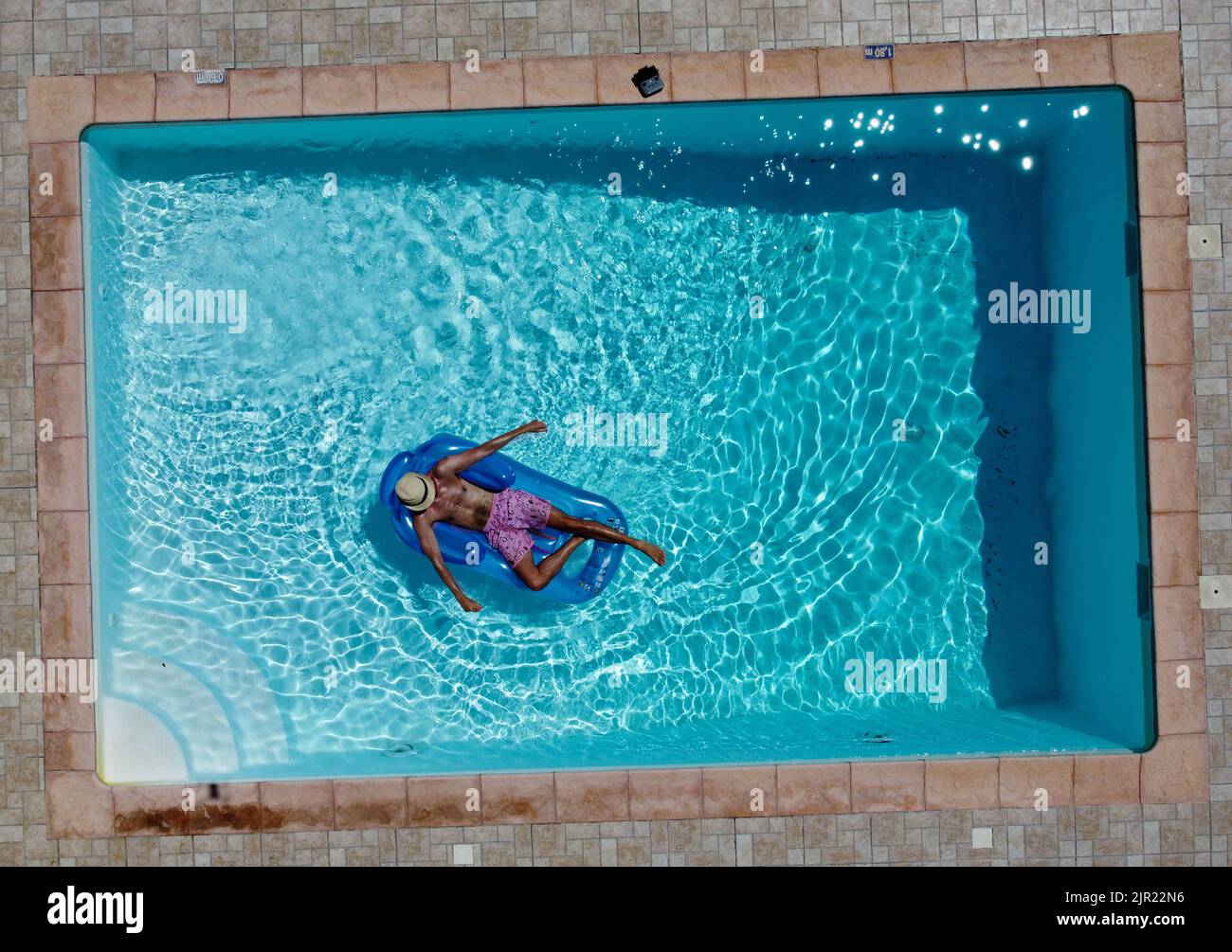 Uomo su un lilo in piscina Foto Stock