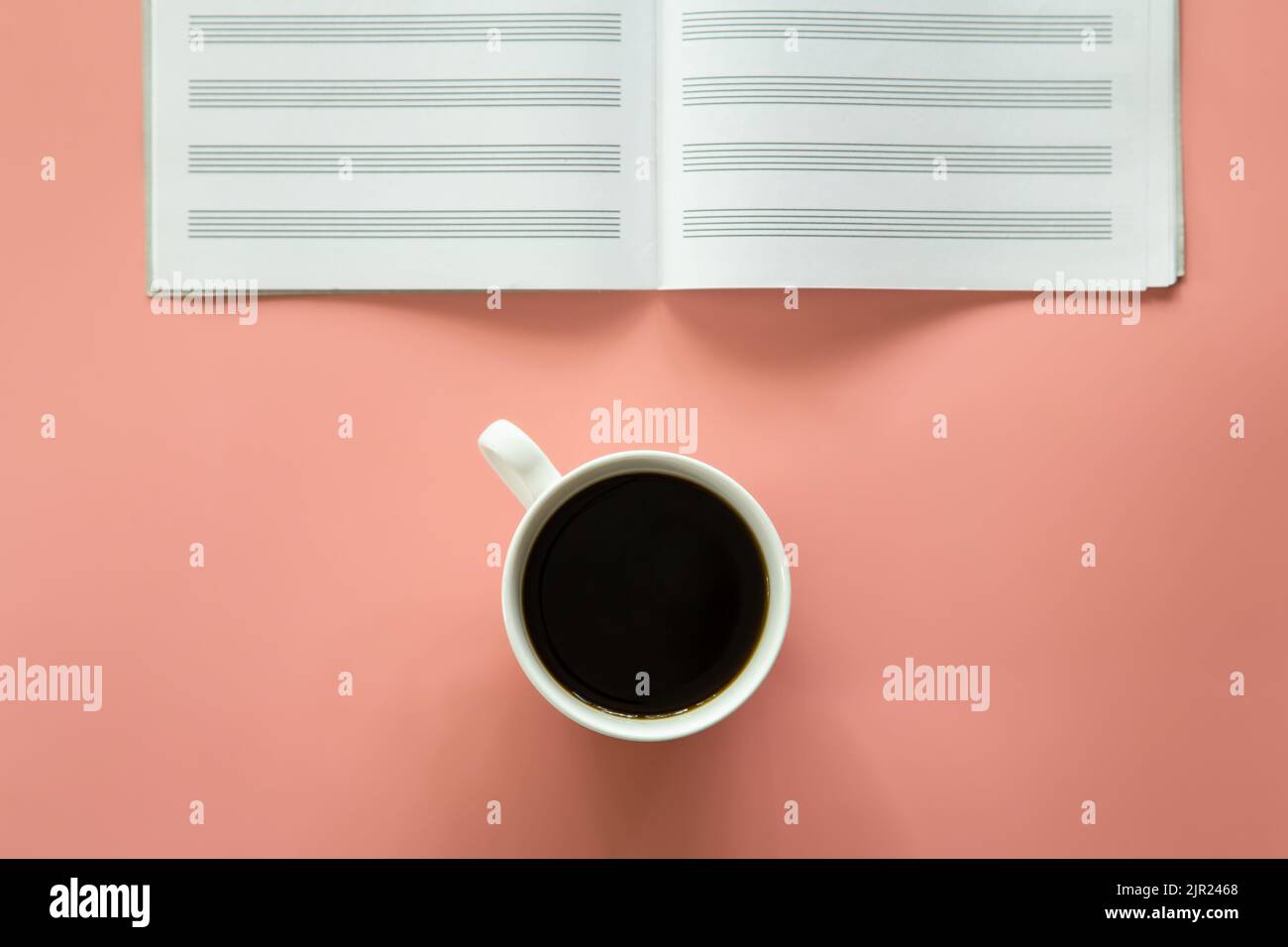 Sfondo rosa minimalista con una tazza di caffè, blocco note, piatto. Foto Stock