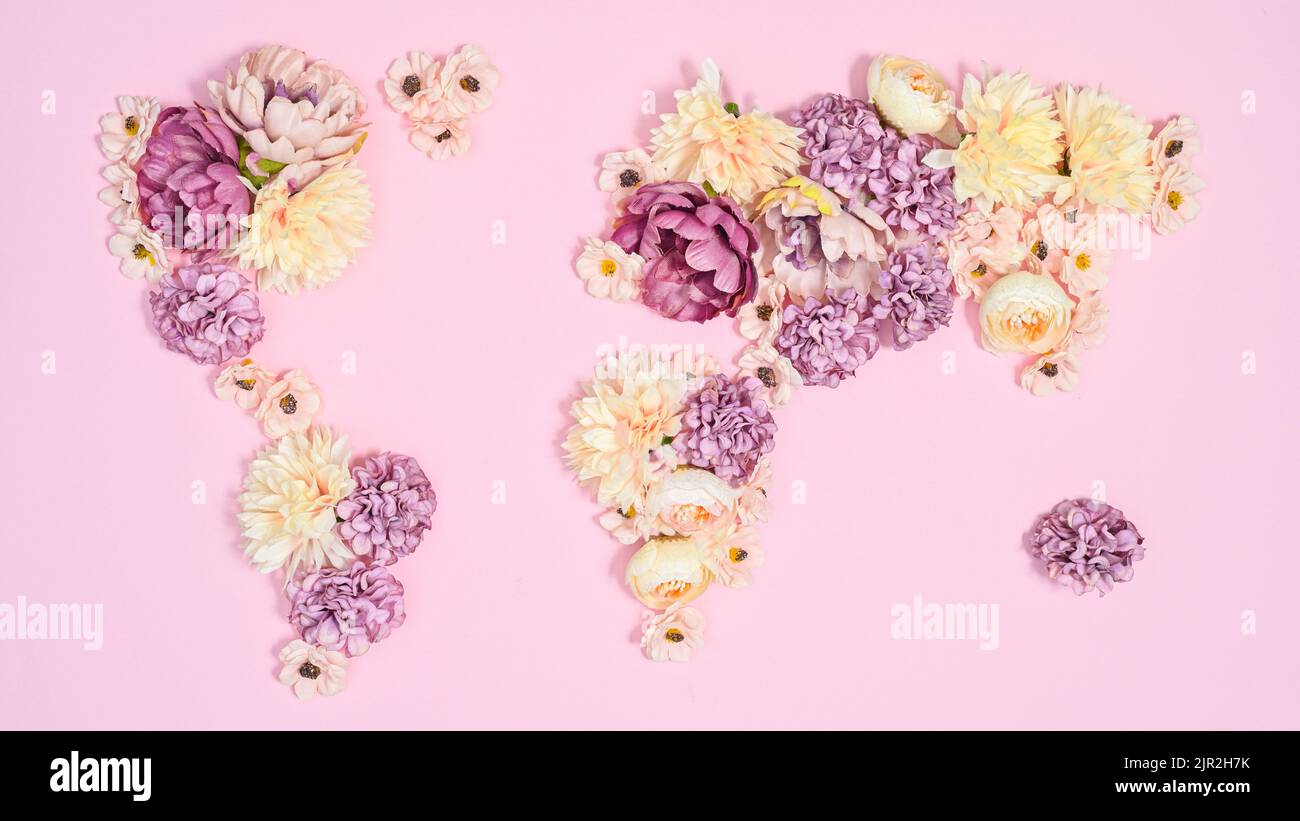 Mappa della Terra creativa su sfondo rosa pastello fatto con fiori freschi naturali. Giacitura piatta Foto Stock
