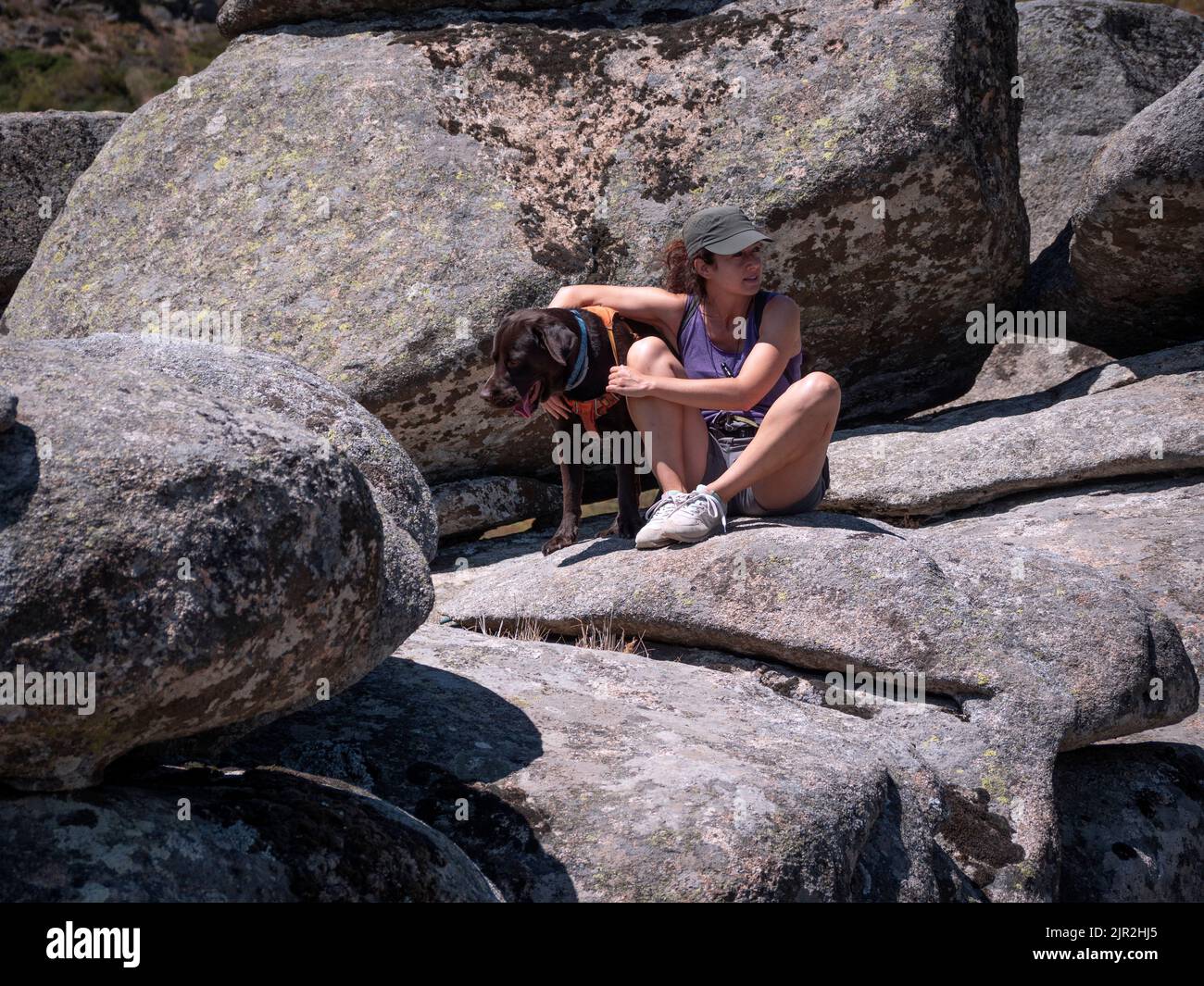 Donna con i suoi due anni di cioccolato labrador Retriever in una passeggiata in montagna. Massi di granito. Foto Stock