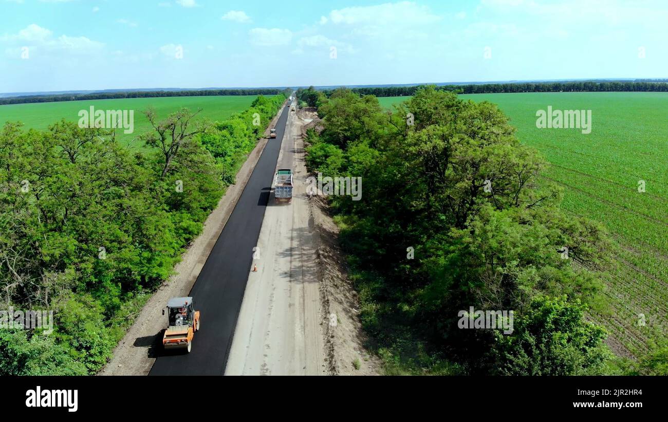 Vista aerea sulla nuova strada asfaltata, riparazione stradale. Su un lato del traffico è steso l'asfalto. A causa della riparazione, il movimento inverso funziona su un lato della strada. Foto di alta qualità Foto Stock