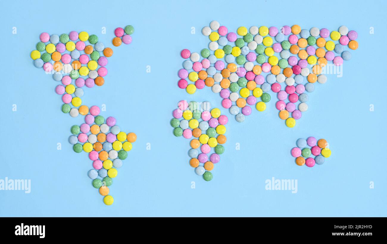 Mappa del mondo fatta con caramelle colorate su blu pastello bakcgorund. Giacitura piatta. Concetto Terra Foto Stock