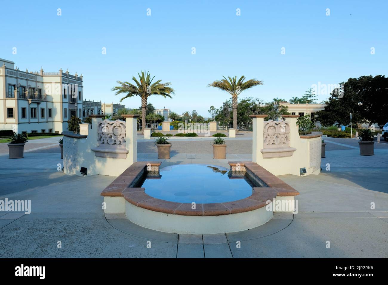 Piscina riflettente nel campus dell'Università di San Diego; passerella e palme si trovano di fronte alla parrocchia di Immaculata, San Diego California. Foto Stock