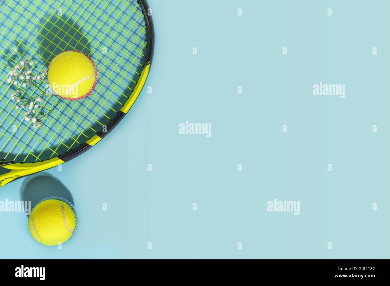 Composizione tennis con palle da tennis gialle e racchetta su sfondo blu di campo da tennis duro con spazio copia. Piatto sportivo. Il concetto di outdo Foto Stock