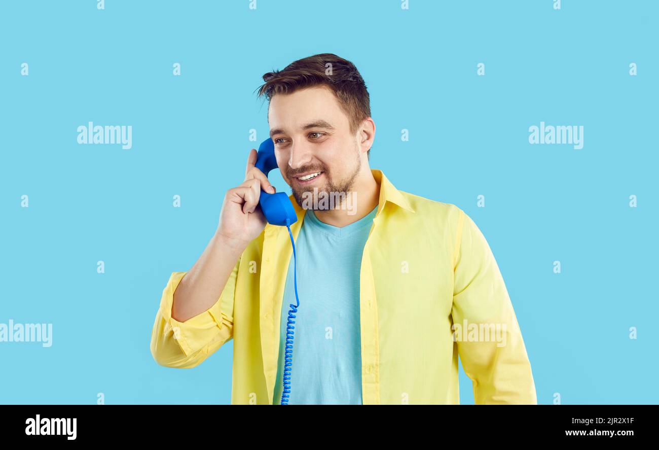 Un uomo sorridente parla al telefono fisso Foto Stock