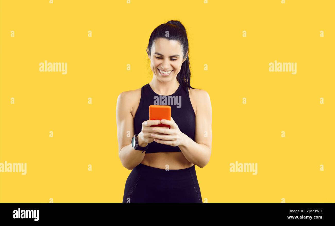 Felice giovane donna sportiva che usa lo smartwatch e l'app per l'allenamento fitness sul suo telefono cellulare Foto Stock