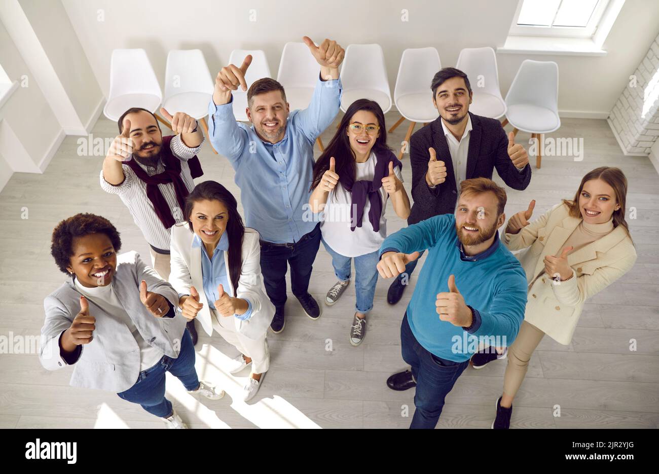 Team di persone che fanno un gesto felice alzando le mani con i pollici a dimostrare il successo. Foto Stock