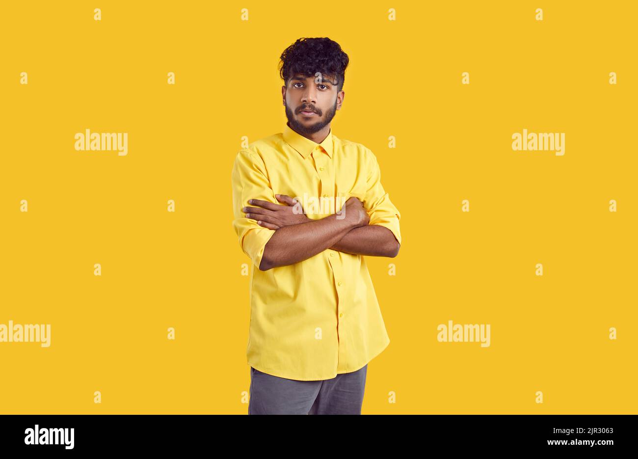 Ritratto di serio ragazzo indiano con insoddisfatta espressione facciale isolato su sfondo arancione. Foto Stock