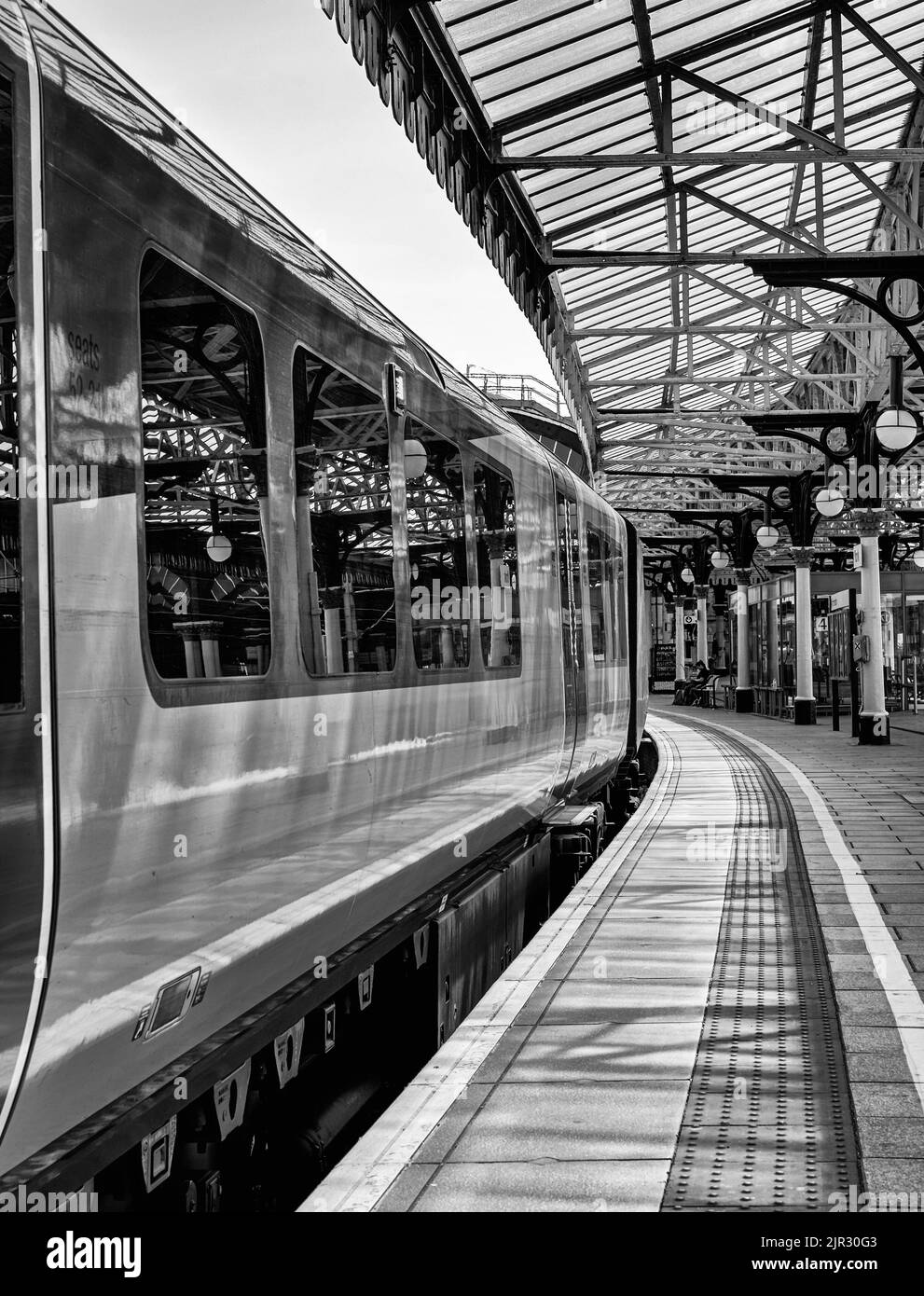 Accanto alla piattaforma della stazione ferroviaria si trova un treno. Sopra si trova uno storico baldacchino del 19th° secolo sorretto da colonne che si riflettono anche nel vento carrozza Foto Stock