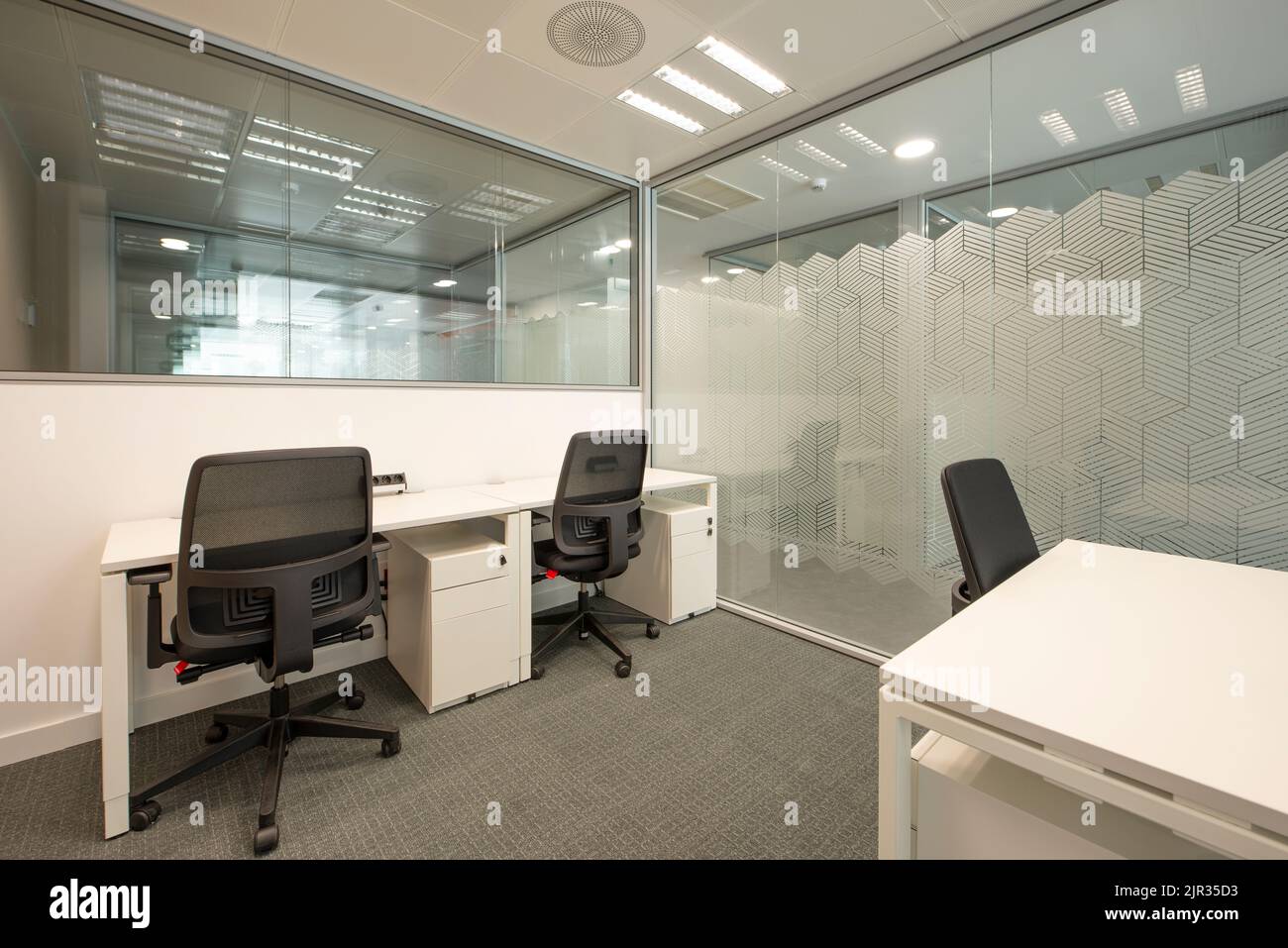 Armadio ufficio con tavoli in legno bianco, sedie girevoli nere, parete e porta scorrevole in vetro Foto Stock