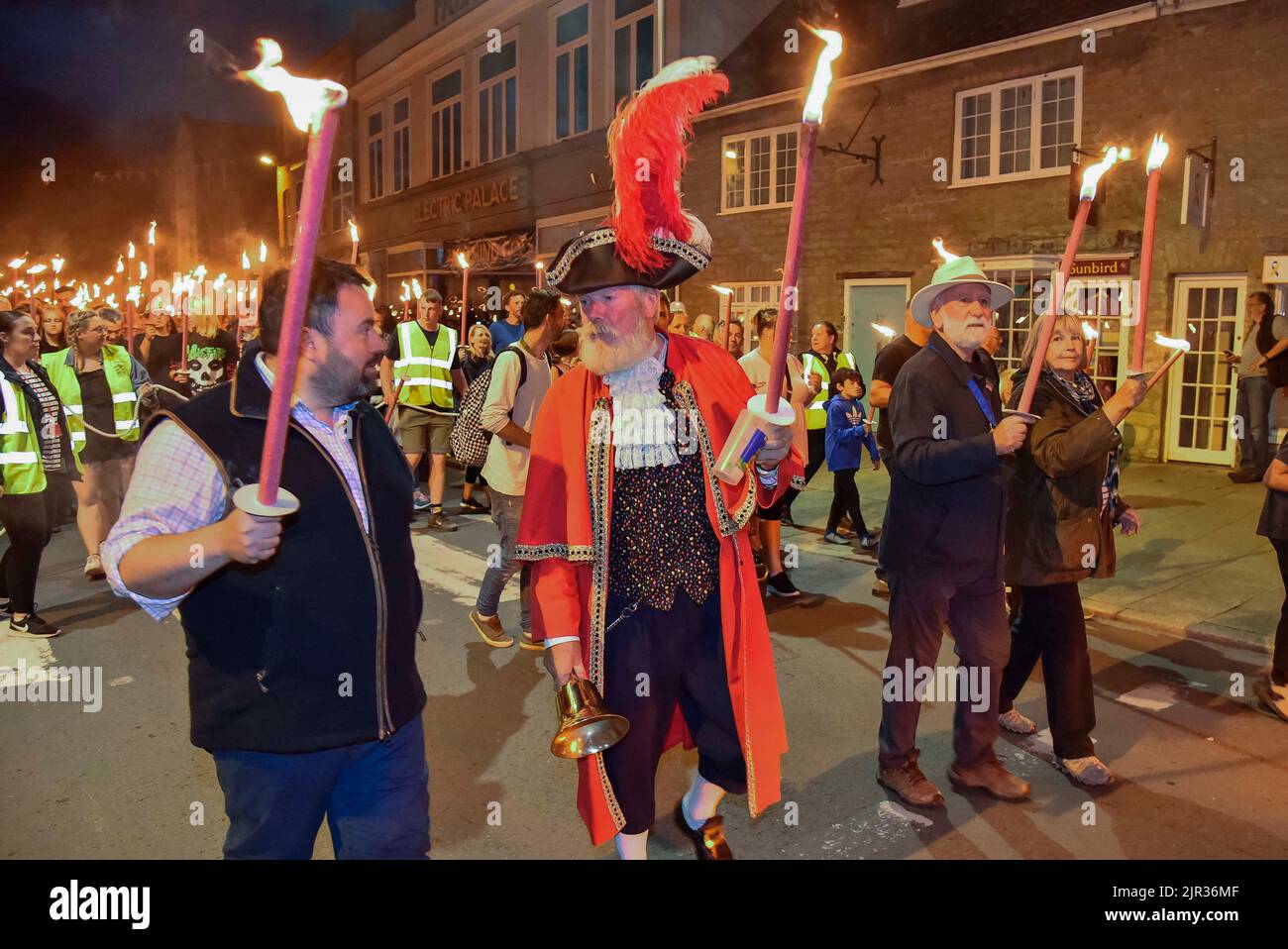 Bridport, Dorset, Regno Unito. 21st agosto 2022. Chris Loder, il cittadino Crier John Collingwood e il sindaco di Bridport Ian Bark con le loro torce accese guidano le centinaia di festaioli che si sono rivelati per l'annuale Bridport Carnival Torchlight Parade a Bridport in Dorset che ritorna dopo un'assenza di tre anni a causa della pandemia di Covid-19. La sfilata di fiaccolate va dal municipio di Bridport a East Beach a West Bay. Picture Credit: Graham Hunt/Alamy Live News Foto Stock