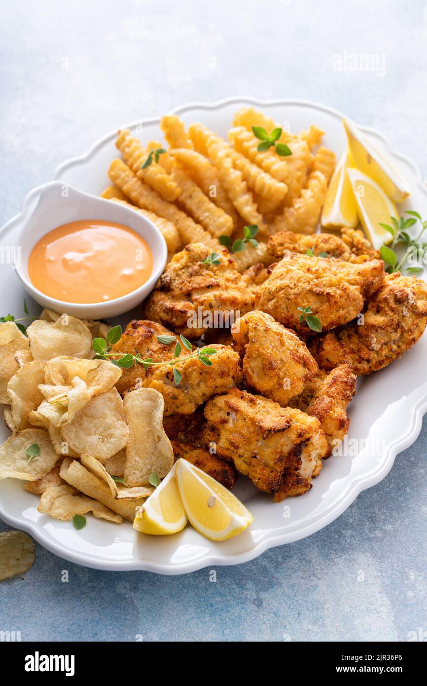 Pesce e patatine su un piatto da portata con salsa da immersione Foto Stock