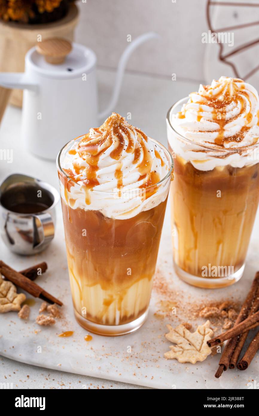Latte speziato di zucca ghiacciato in bicchieri alti con panna montata Foto Stock