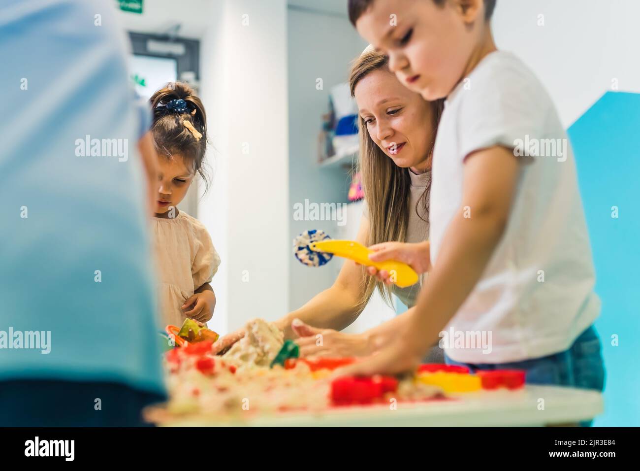 insegnante che gioca con sabbia cinetica con i suoi bambini in asilo, attività creative. Foto di alta qualità Foto Stock