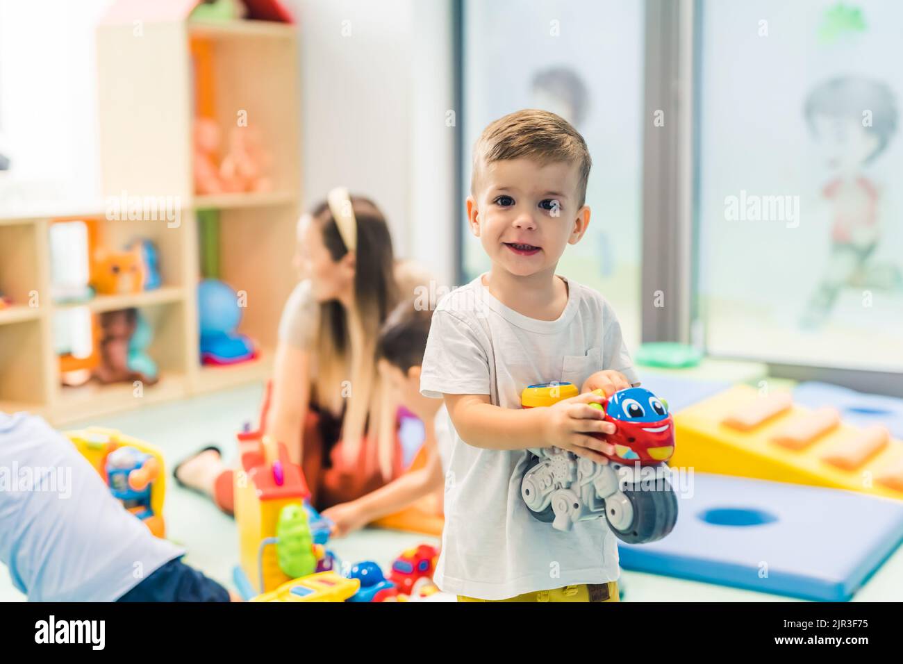 Piccolo ragazzo caucasico che si gode nella sala giochi dell'asilo. Foto di alta qualità Foto Stock