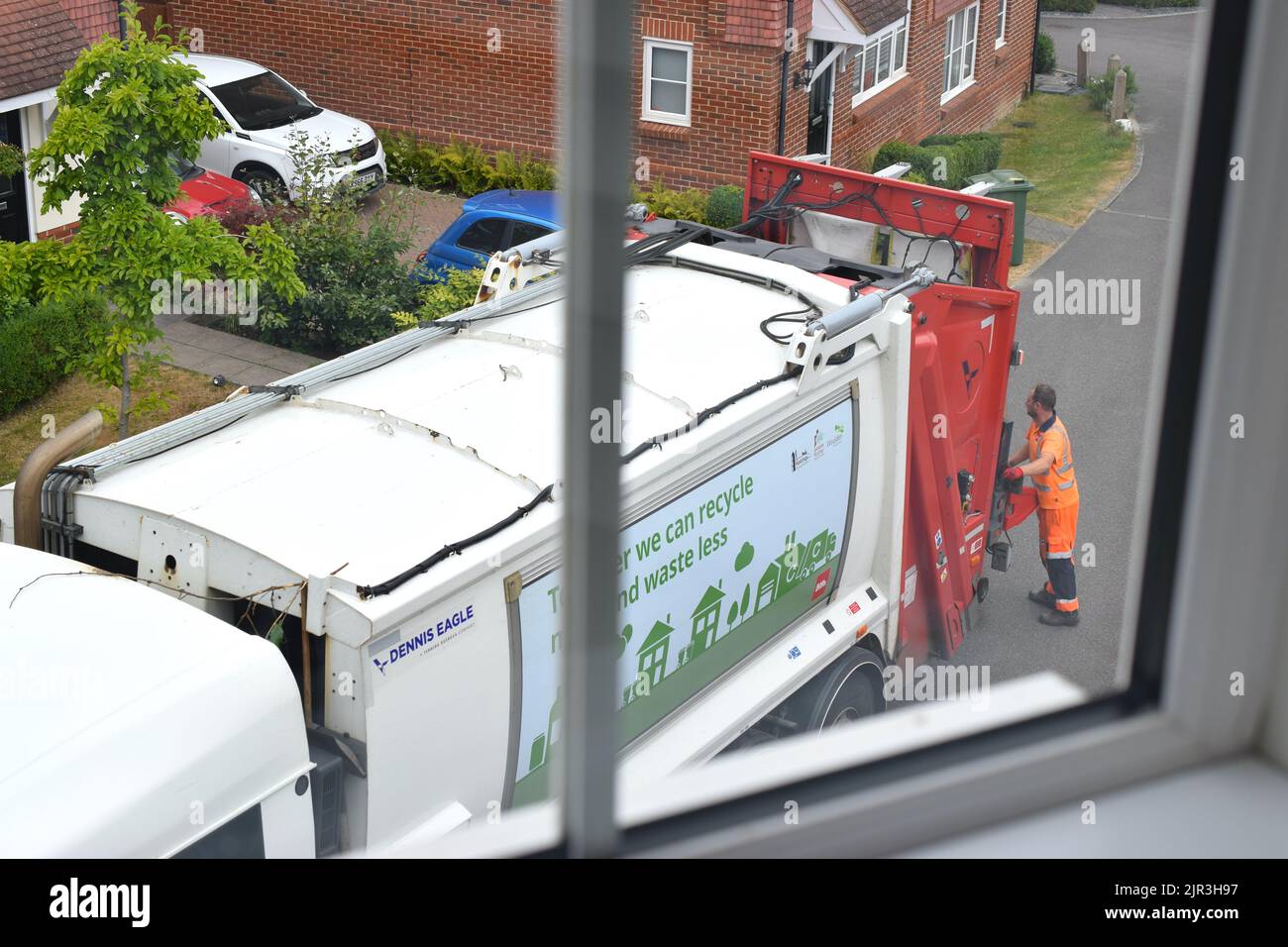 Camion rifiuti e un lavoratore su strada residenziale. Foto Stock