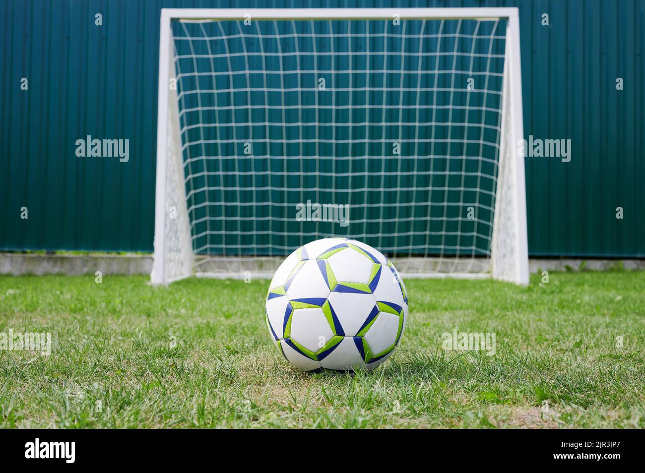 Pallone da calcio e cancello tema. Campo sportivo in erba verde Foto Stock