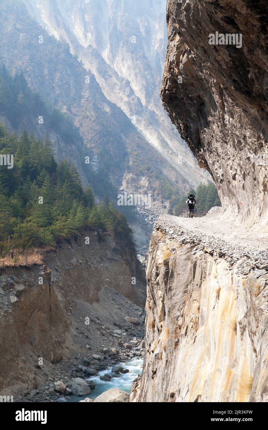 Uomo sulla strada, strada rocciosa in giro circuito Annapurna sentiero trekking, Nepal Foto Stock