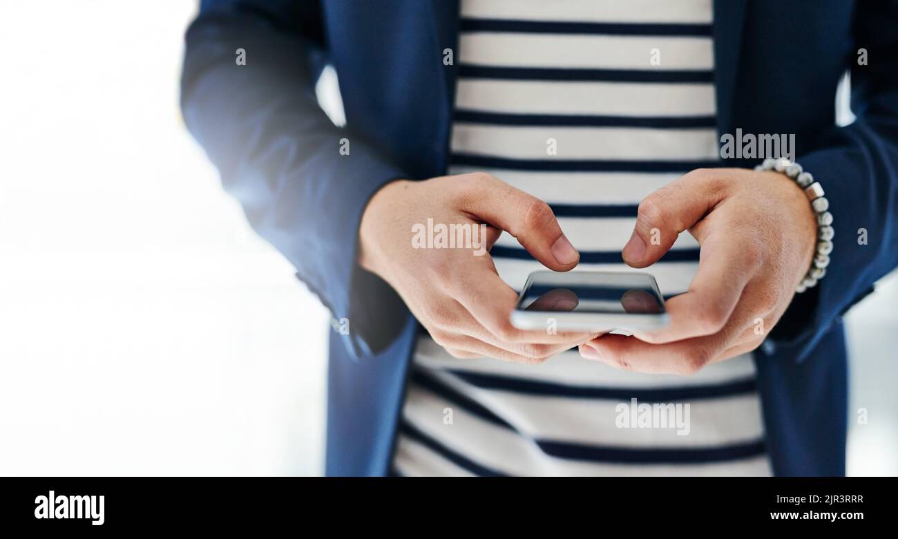 Rimani in contatto, tieniti aggiornato. Un uomo d'affari che utilizza un telefono cellulare in un ufficio moderno. Foto Stock