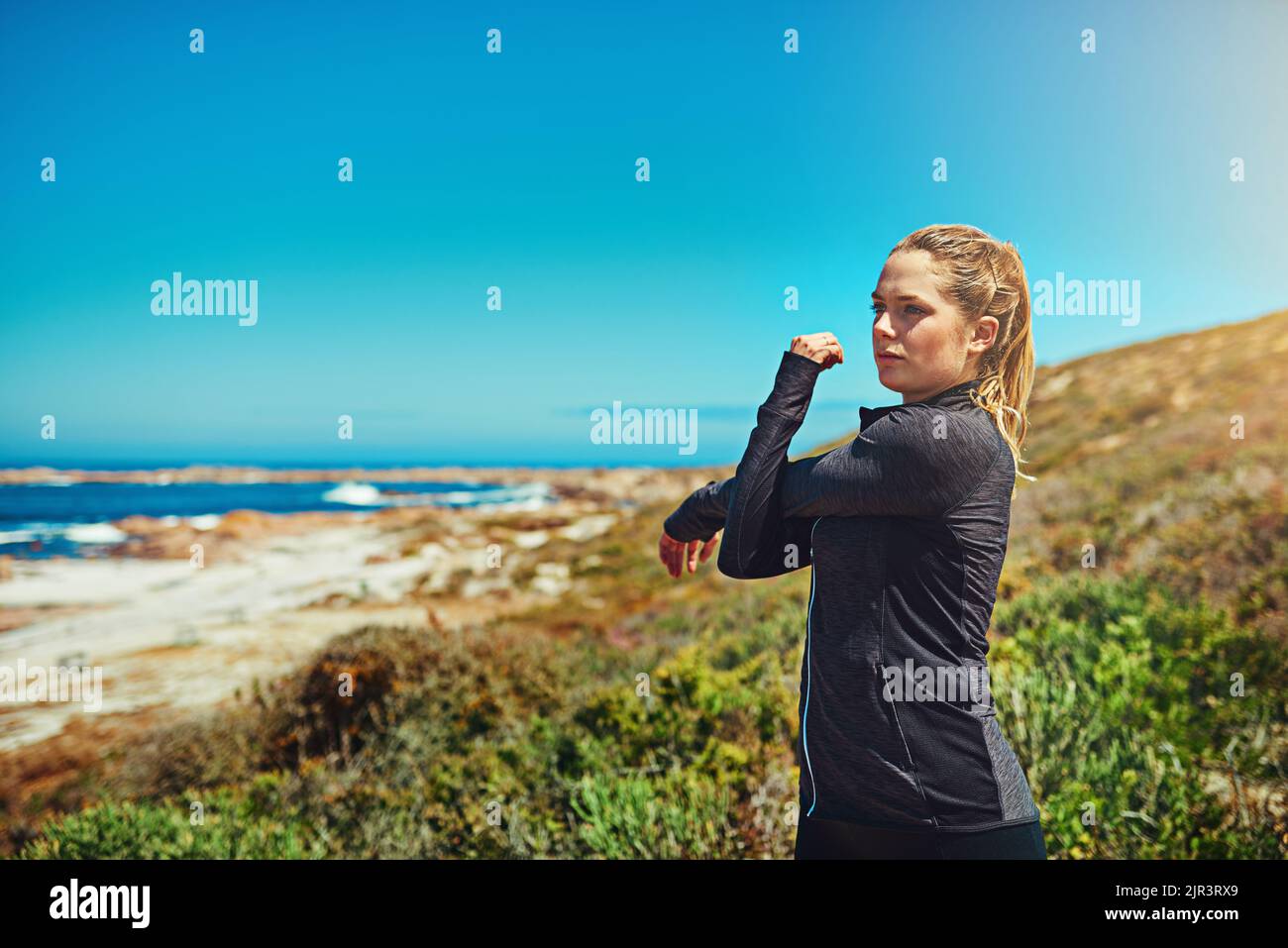 Lo stretching è essenziale per un ottimo allenamento. Una giovane donna sportiva che si stretching prima del suo allenamento all'aperto. Foto Stock