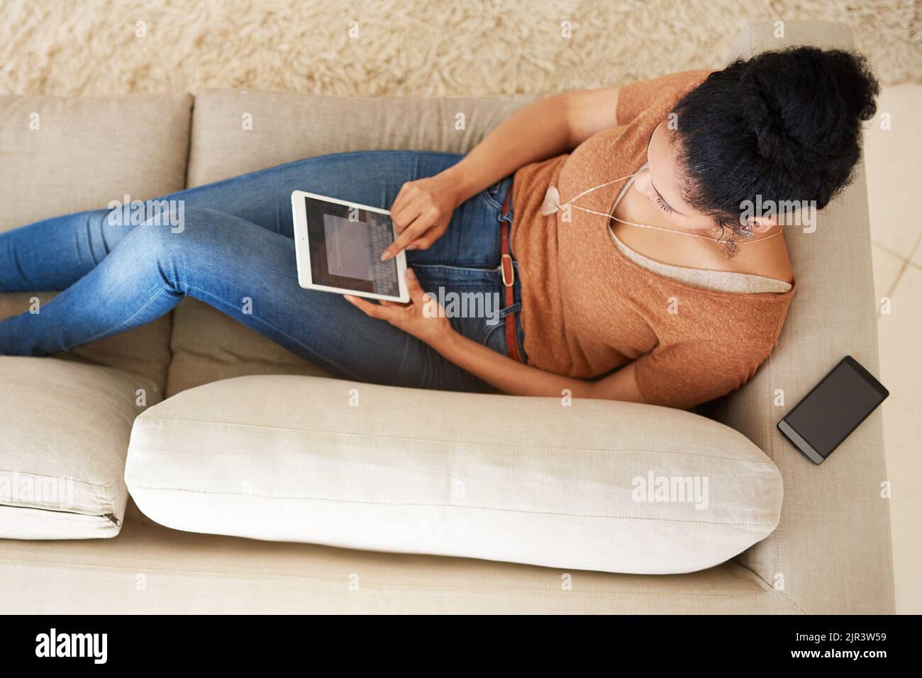 Piccolo dispositivo ma molto comodo. Una donna irriconoscibile che usa un tablet a casa. Foto Stock