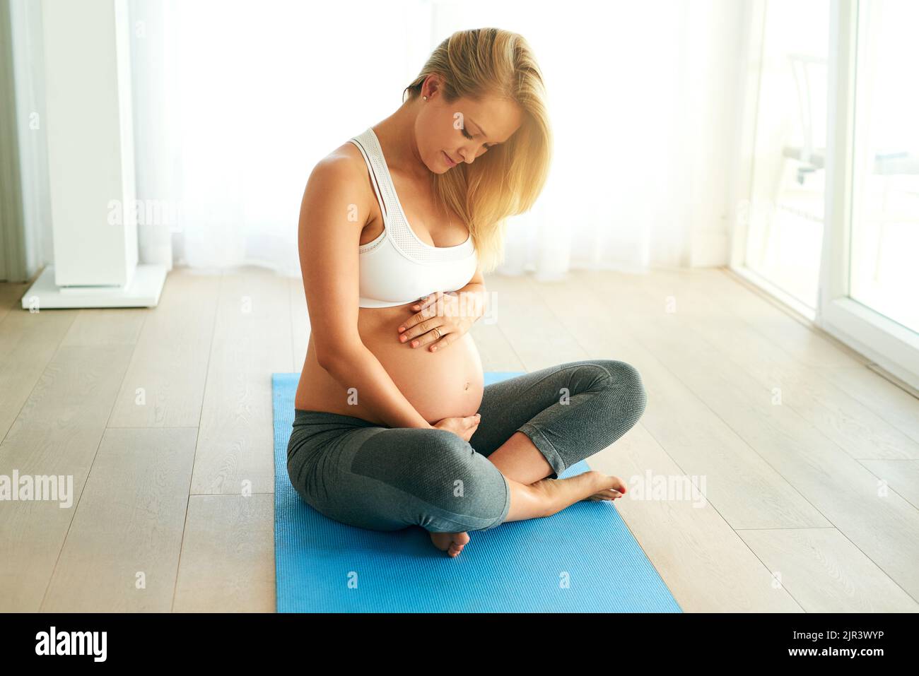 Mamma sana, bambino sano. Una donna incinta che lavora su un materassino per l'esercizio fisico a casa. Foto Stock