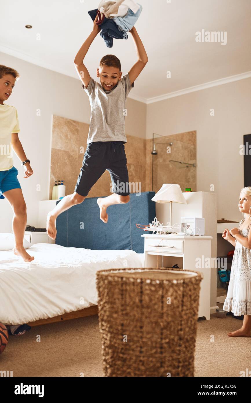 HES andando per la grande spazzatura di slam. Un ragazzino che getta il bucato in un cestino mentre i suoi fratelli lo guardano. Foto Stock