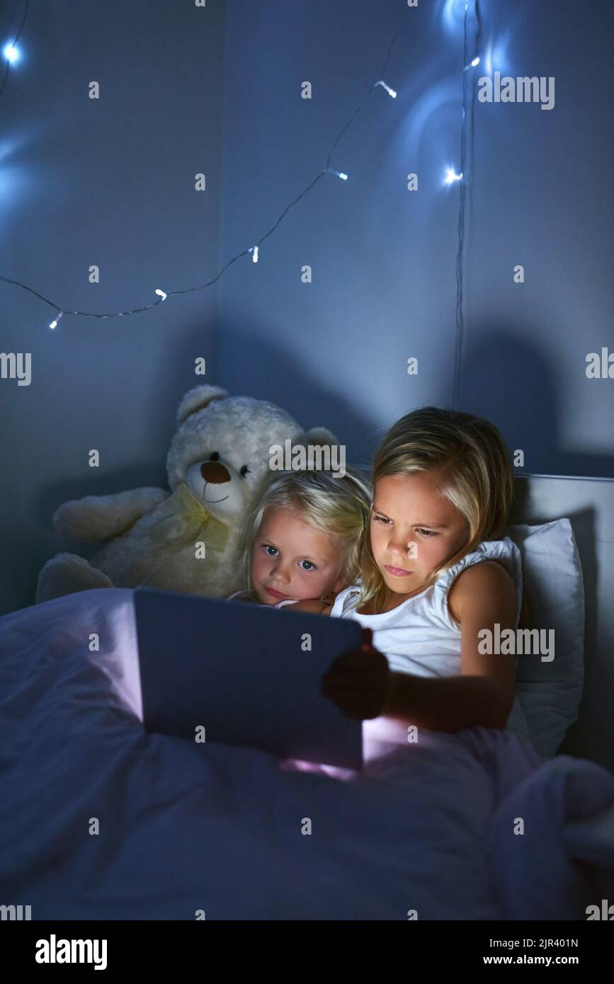 Imparare e crescere nell'era digitale: Due bambine che usano un tablet digitale prima di andare a letto. Foto Stock