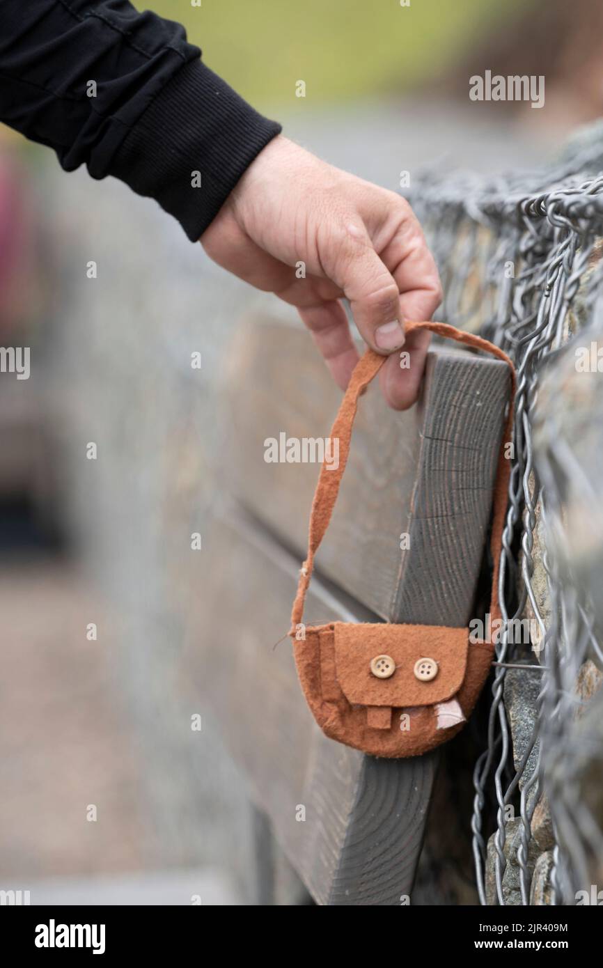 Qualcuno ha perso una borsa. Una mano dell' uomo prende una cosa persa trovata - una borsa da donna dei bambini piccoli . Oggetti abbandonati o abbandonati, persi e trovati. Foto Stock