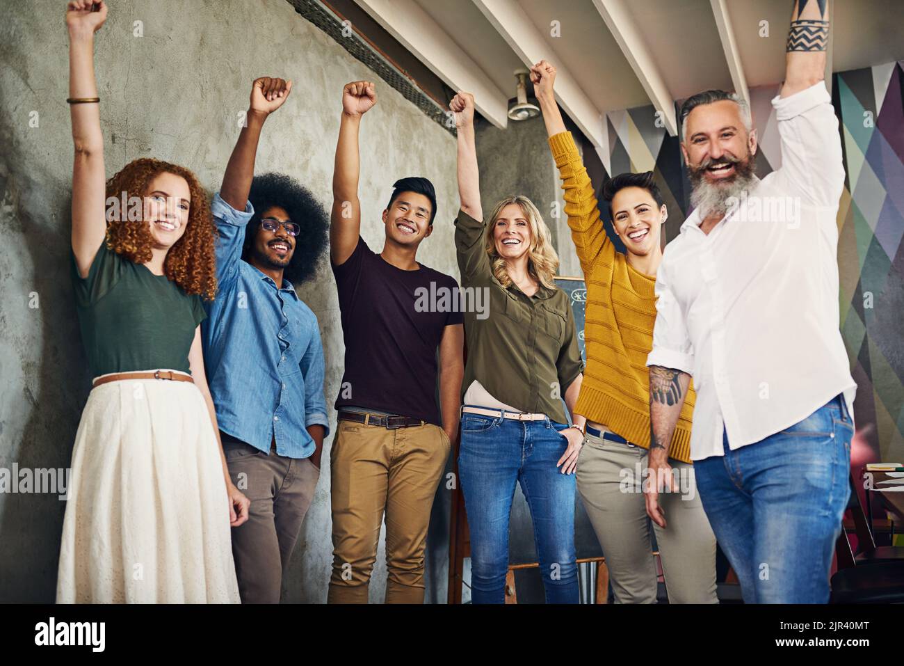 La sua unica grandezza da qui in avanti per noi. Ritratto di un gruppo di designer che alzano i pugni in un ufficio. Foto Stock