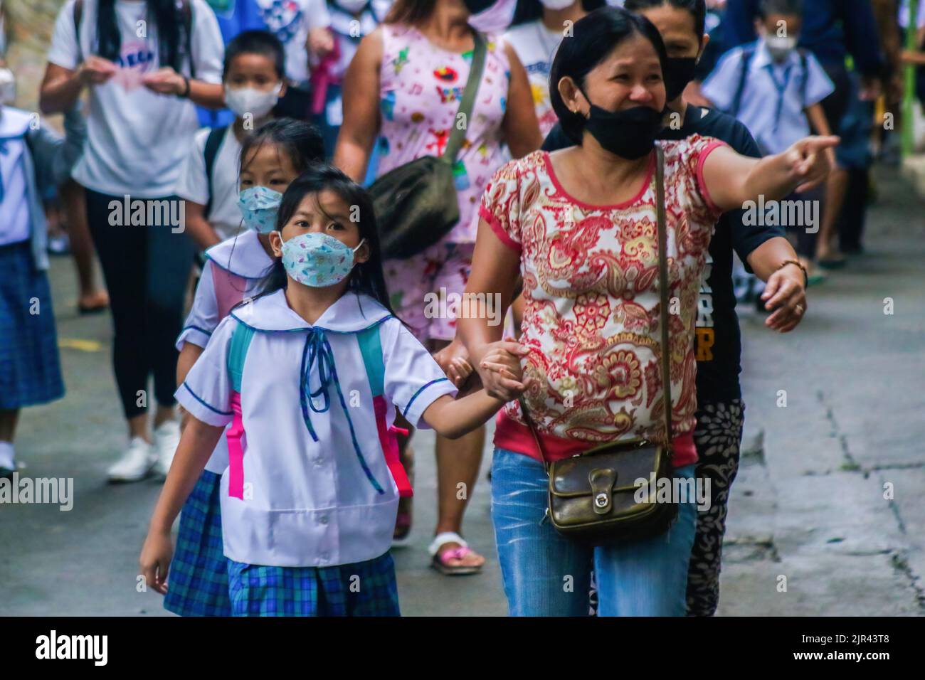 Studenti in uniforme accompagnati dai genitori il primo giorno delle lezioni di persona. Le Filippine iniziano le lezioni di persona dopo 2 anni di scuola virtuale a causa della pandemia. Il Dipartimento dell'Educazione (DepEd) ha detto che ci sono 27.691.191 studenti iscritti per l'anno scolastico 2022-2023. Il 19% degli studenti nelle Filippine è completamente vaccinato e il 20% ha ricevuto solo la prima dose di vaccino COVID-19, ha affermato DedePed. Il protocollo del dipartimento è, se ci sono casi di COVID-19 o alcuni studenti che sperimentano sintomi simil-influenzali, definitivamente si sposteranno dalle lezioni di persona di nuovo a. Foto Stock