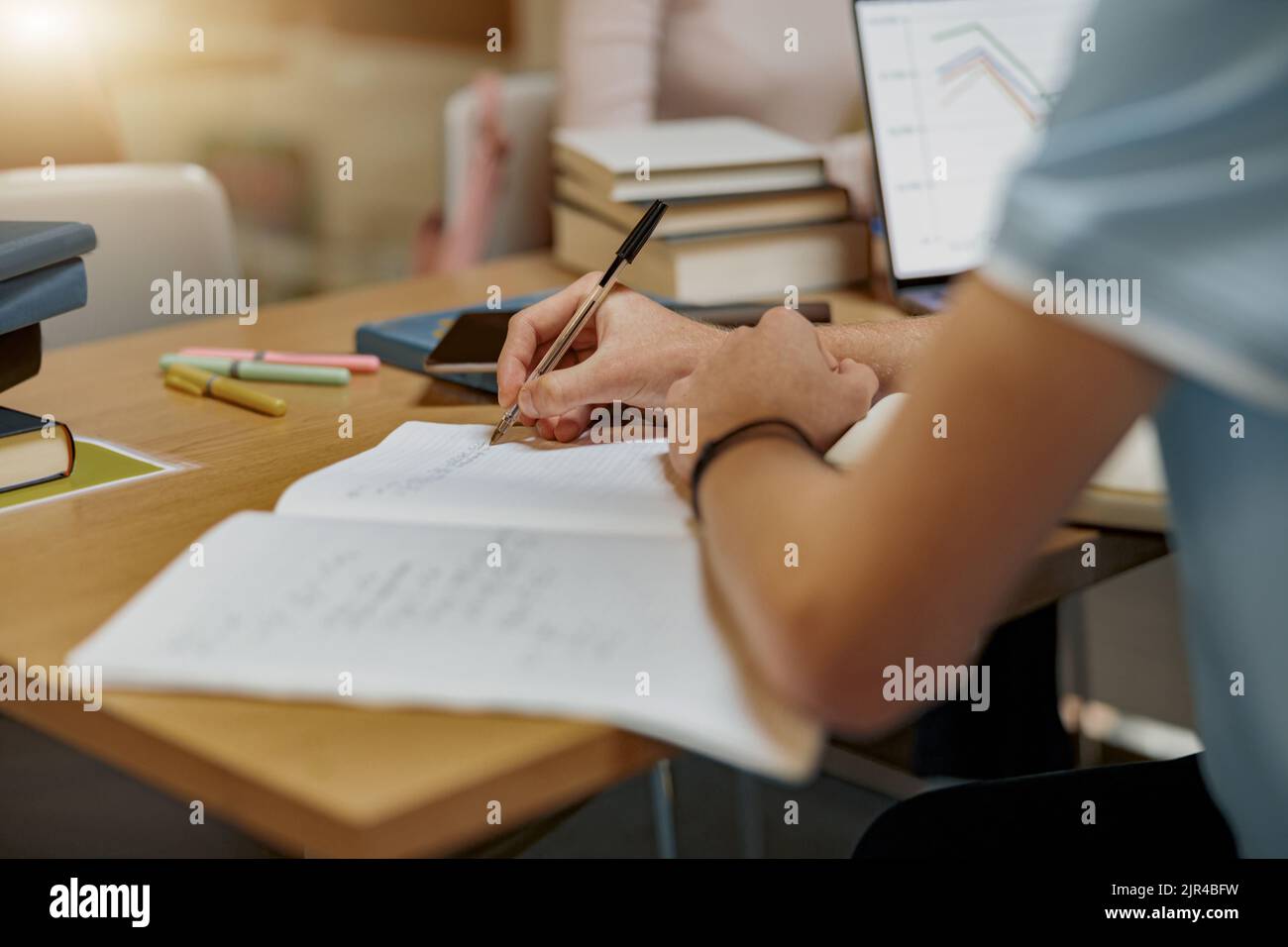 Primo piano dello studente si trova nella biblioteca, prepararsi per l'esame e prendere appunti nel notebook Foto Stock