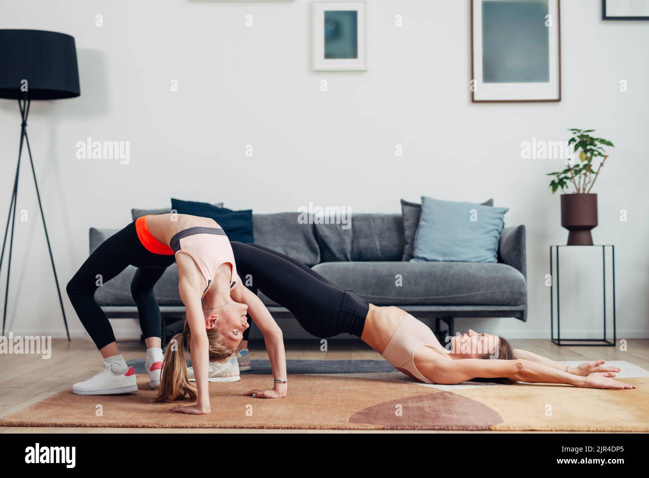 Home allenamento madre e figlia fare ponte e ponte gluteale. Foto Stock