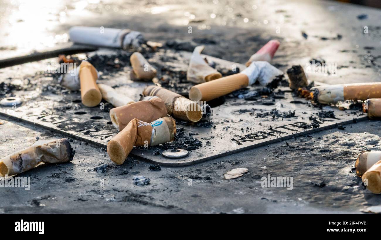 I mozziconi di sigaretta usati gettati sulla superficie sporca del posacenere Foto Stock