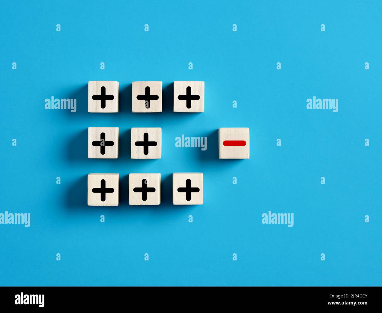 Icone più e meno su cubi di legno. Separare il negativo dal positivo, rimuovendo le debolezze o negatività, il pensiero positivo, il feedback negativo Foto Stock