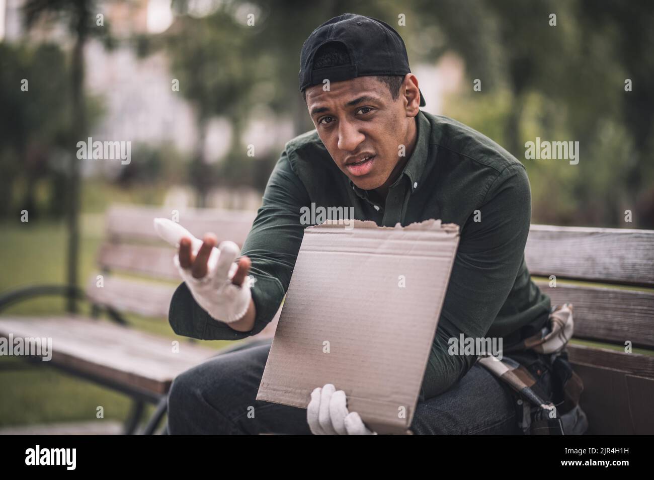 Uomo con mano tesa che guarda infelicatamente la telecamera Foto Stock